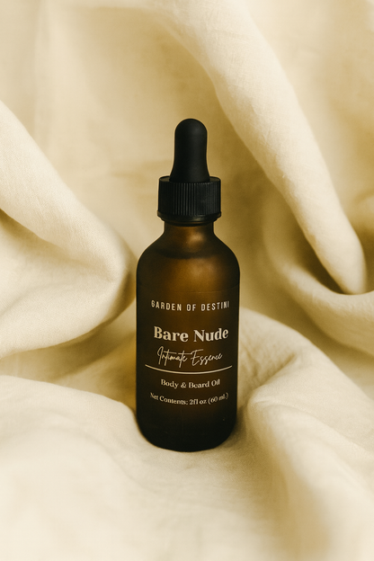 A 2oz amber glass dropper bottle of Garden of Destini Bare Nude Intimate Essence Body & Beard Oil rests on soft beige fabric. The folds of the fabric create a warm, elegant backdrop that highlights the minimalist white label and luxurious aesthetic of the product.