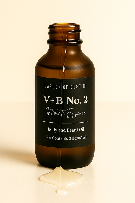 Amber glass bottle labeled “GARDEN OF DESTINI – V+B No. 2 – Intimate Essence – Body and Beard Oil – Net Contents 2 fl oz (60mL),” displayed upright on a light beige background with the cap removed, showcasing a clear, minimalist aesthetic.